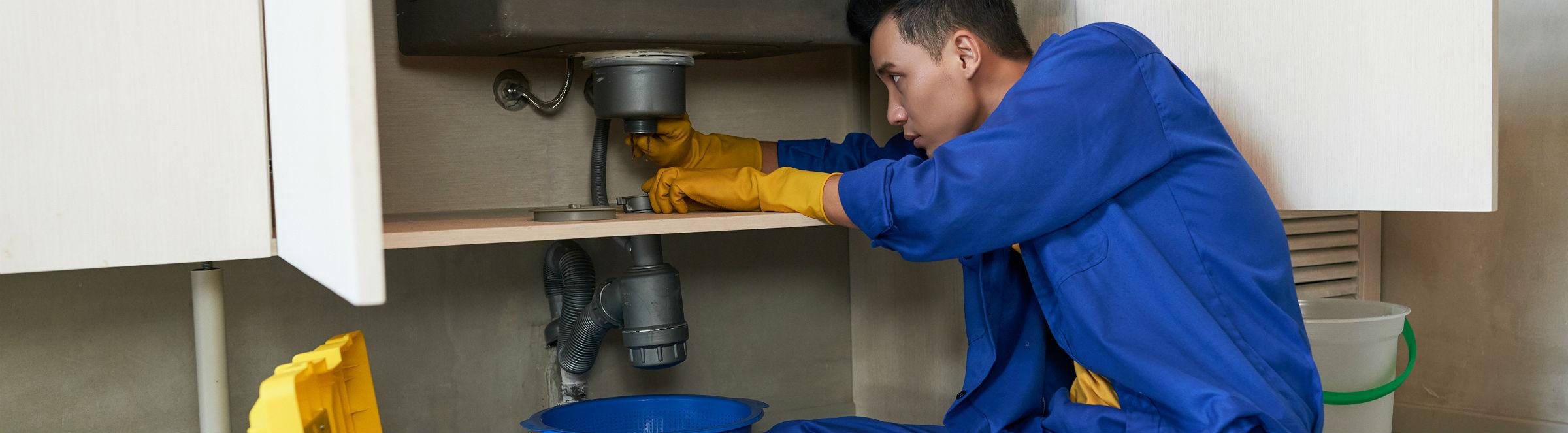Un plombier répare un évier dans une cuisine